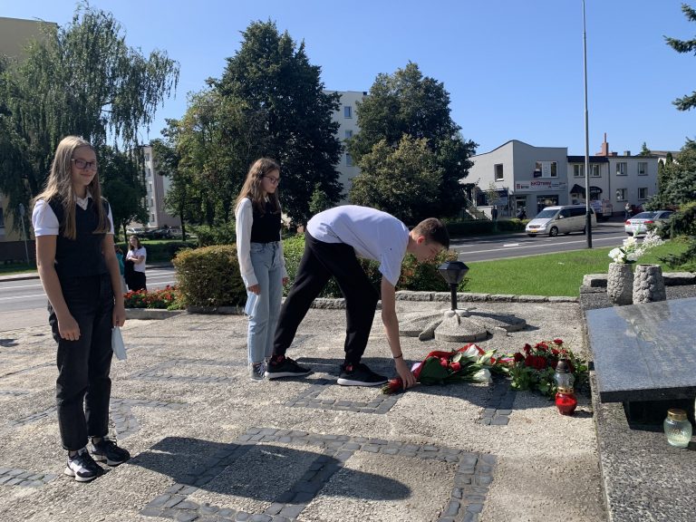 uczniowie składają kwiaty na pomniku